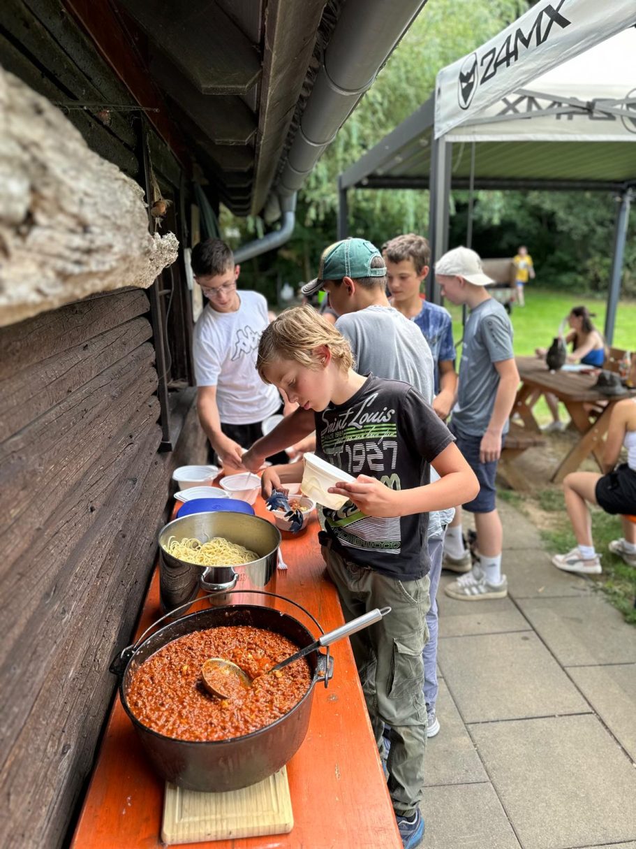 Gemeinsam feiern Jugendliche stehen an einem Buffet mit Töpfen, während sie sich Essen servieren.