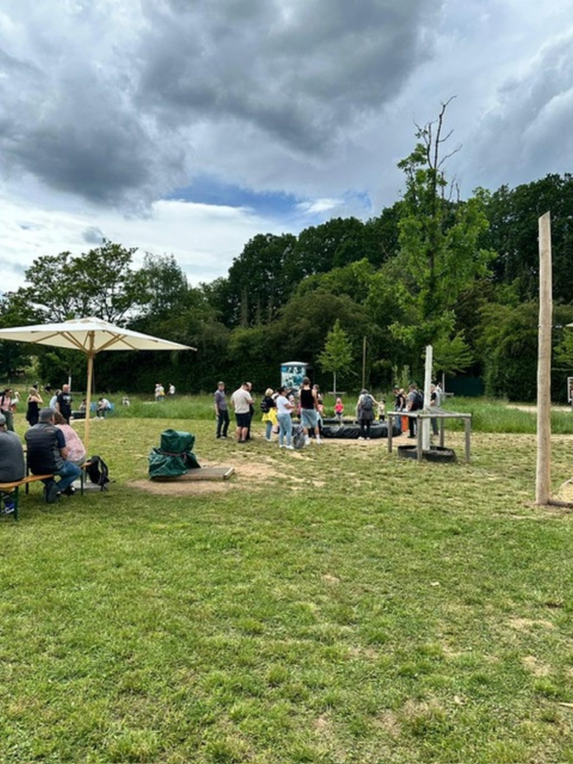 Es gab jede Menge zu entdecken. Grüne Wiese mit Menschen, die unter einem Sonnenschirm und an Spielgeräten sitzen.