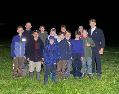 Gruppe von Jungen und Männern im Freien bei Nacht, lächelnd und in Freizeitkleidung.