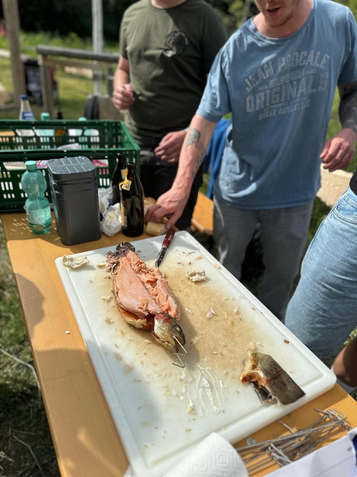 Sehr lecker Zwei Personen am Tisch beim Zubereiten von frischem Fisch auf einem Schneidebrett.
