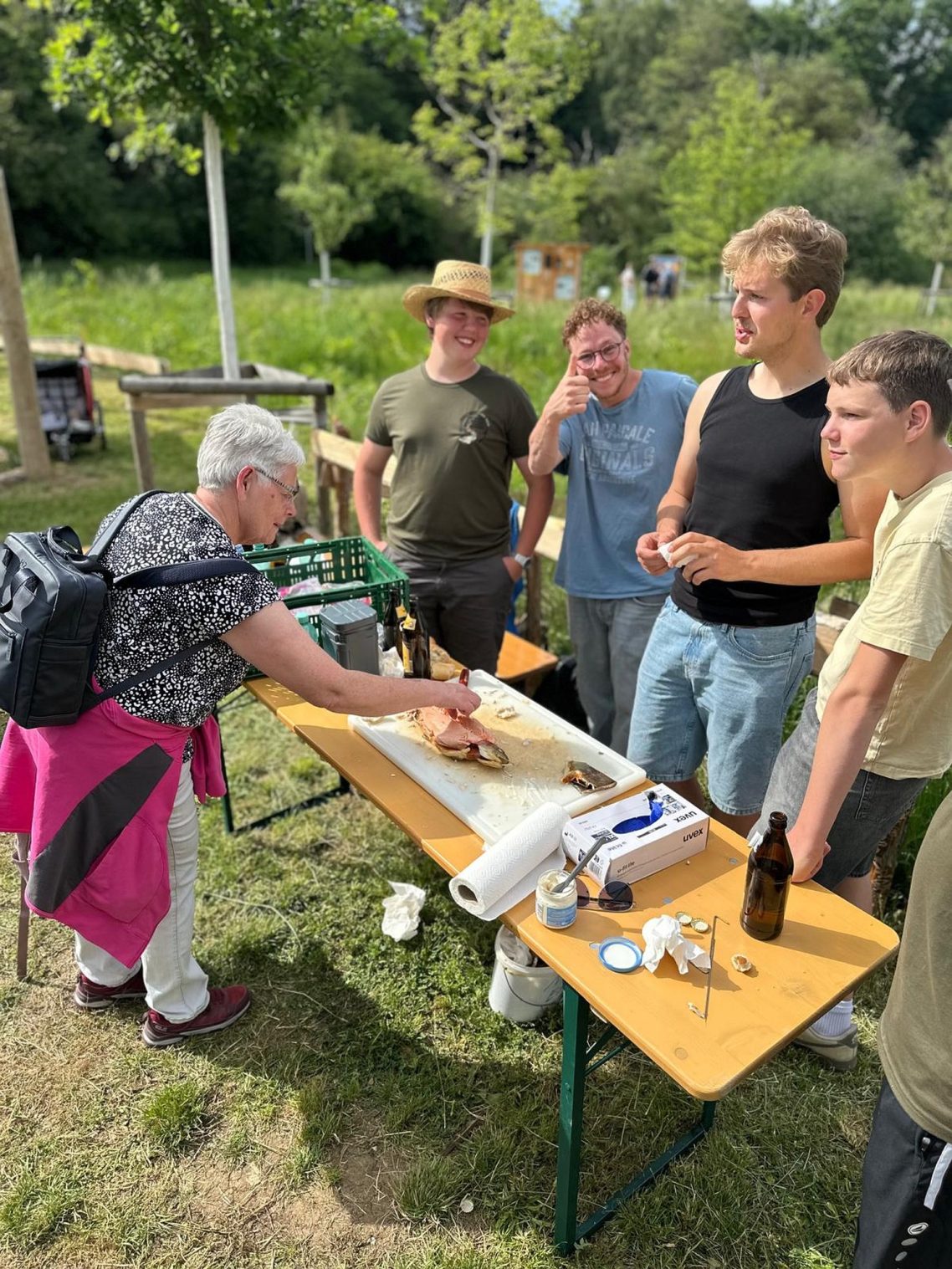 Eine Kostprobe für das Publikum Eine Gruppe von fünf Personen, die an einem Tisch im Freien arbeiten und kommunizieren.