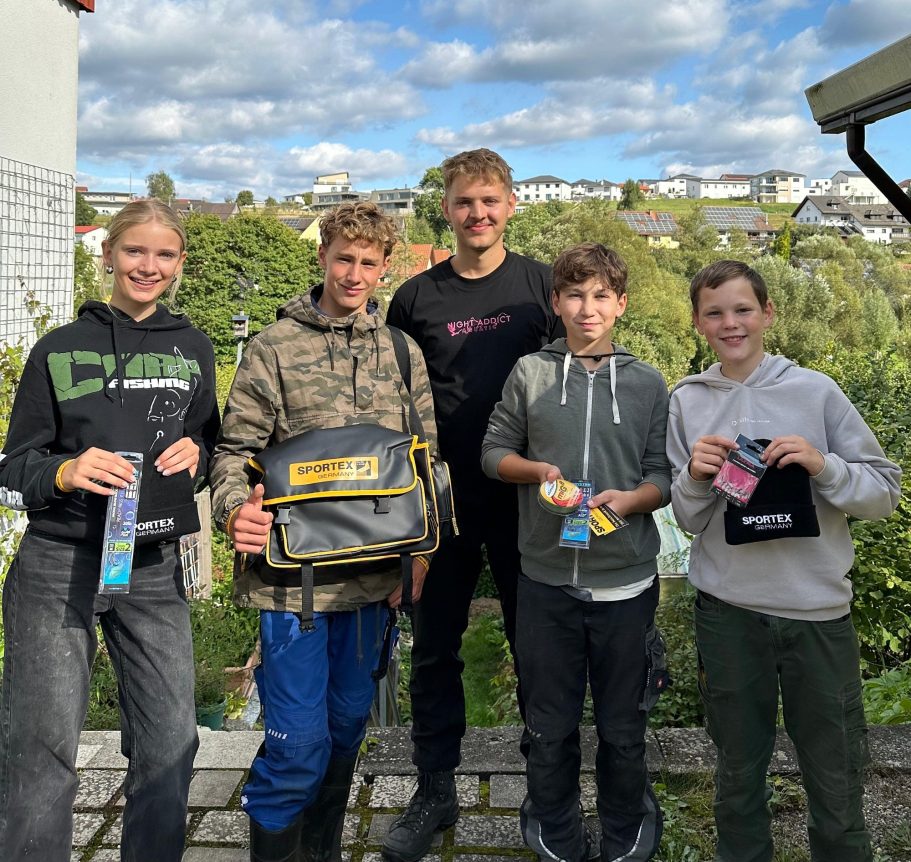 Wettkampf Gruppe von fünf Personen im Freien, die mit Ausrüstung in der Hand lächeln.