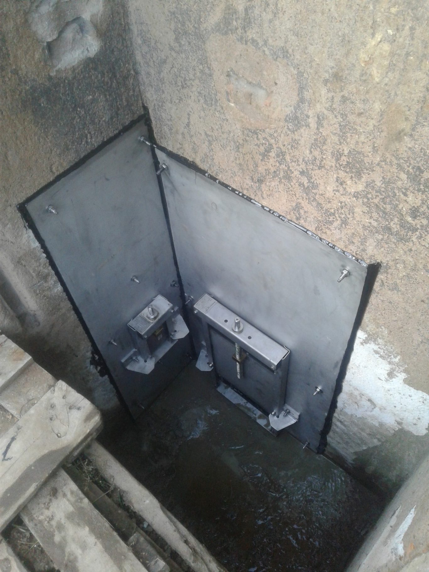 Ablassventil für Teiche in Mönch Ein dunkler, feuchter Raum mit Metalltür und sichtbaren elektrischen Geräten.